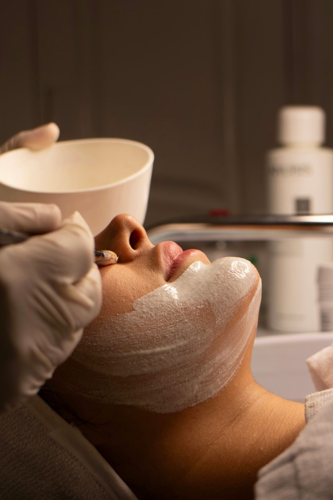 A facial mask being applied with a bowl and gloved hand