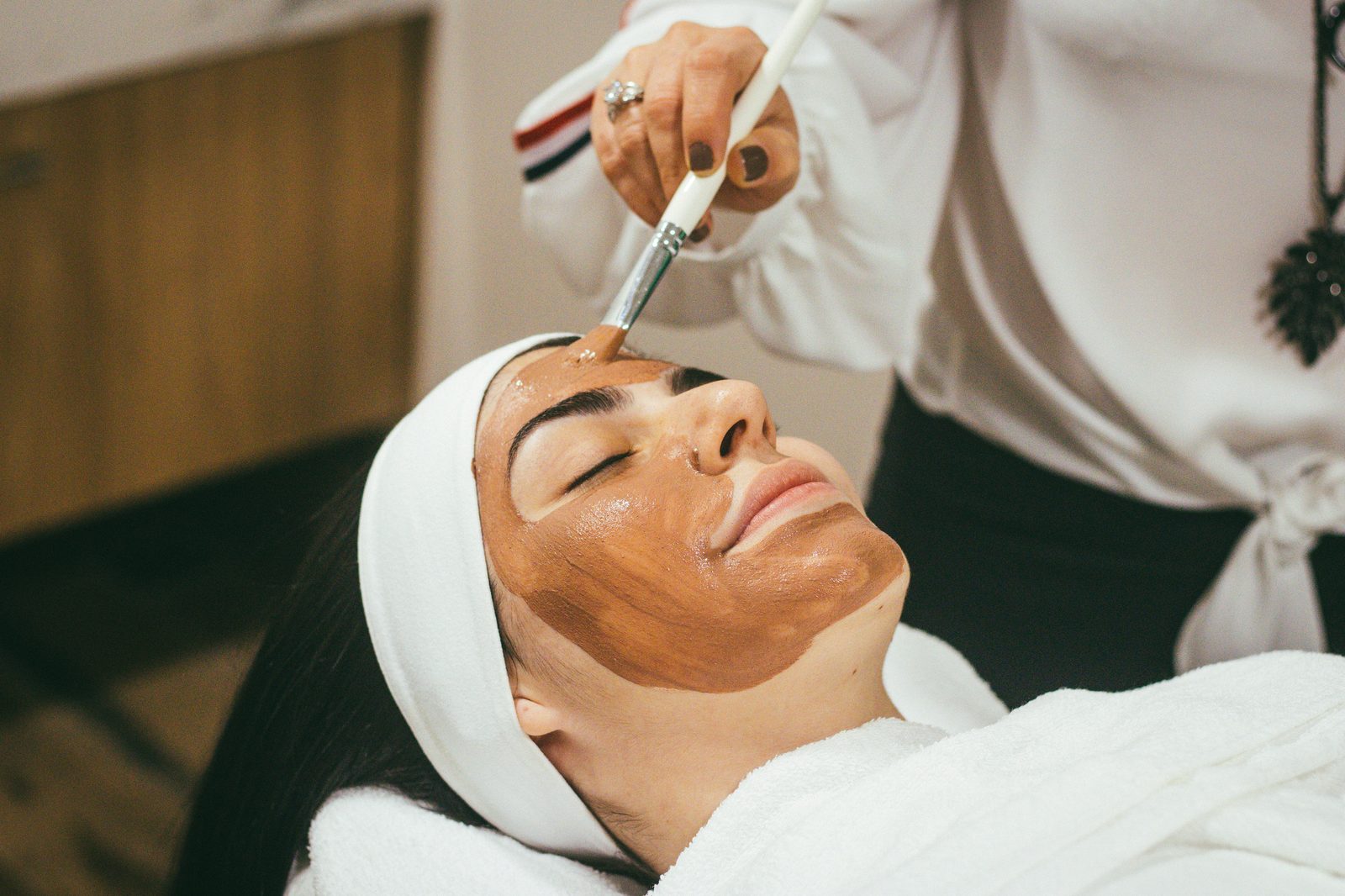 A therapist applying a clay mask with a brush
