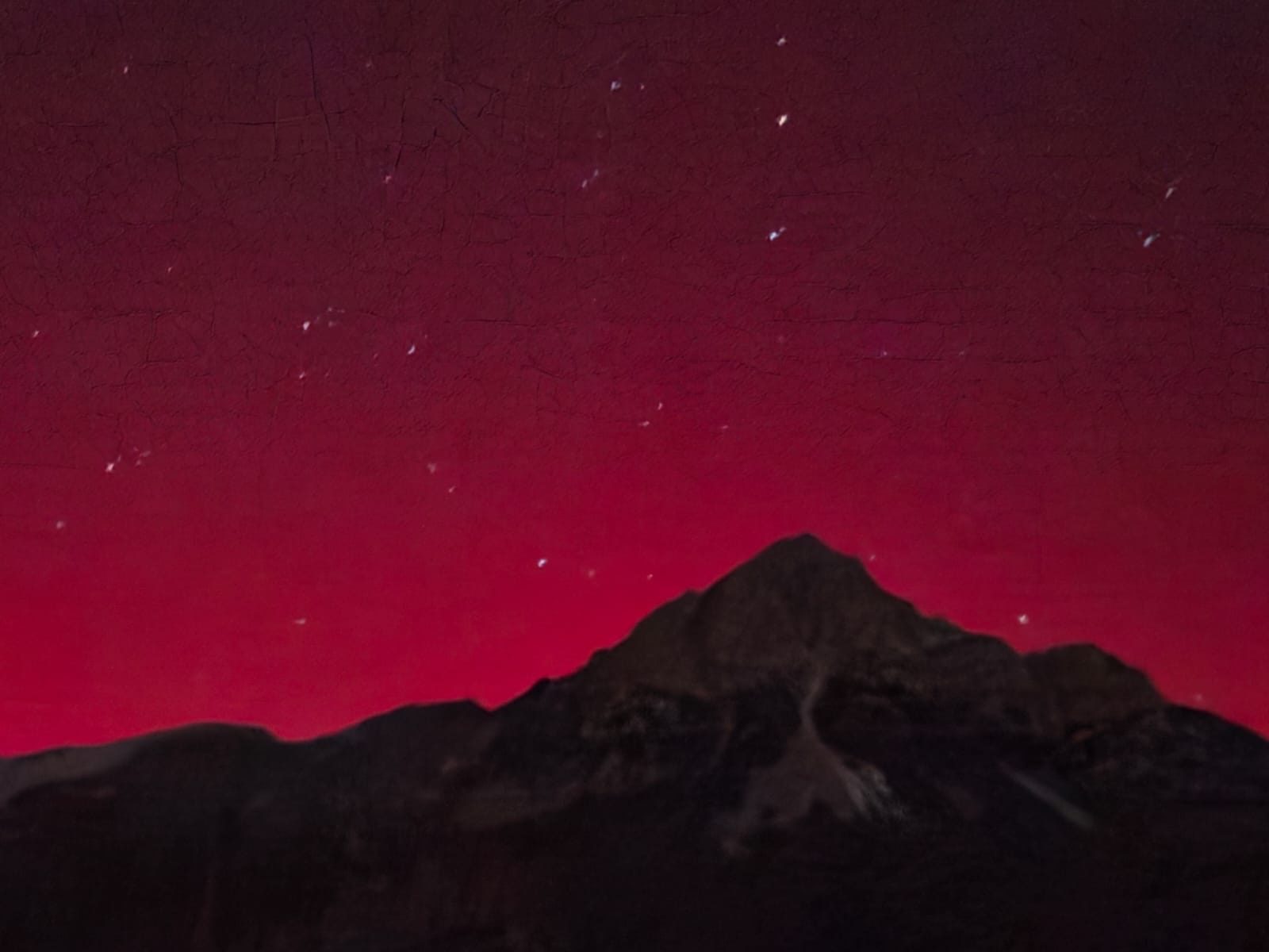 A mountain silhouetted against a deep red night sky