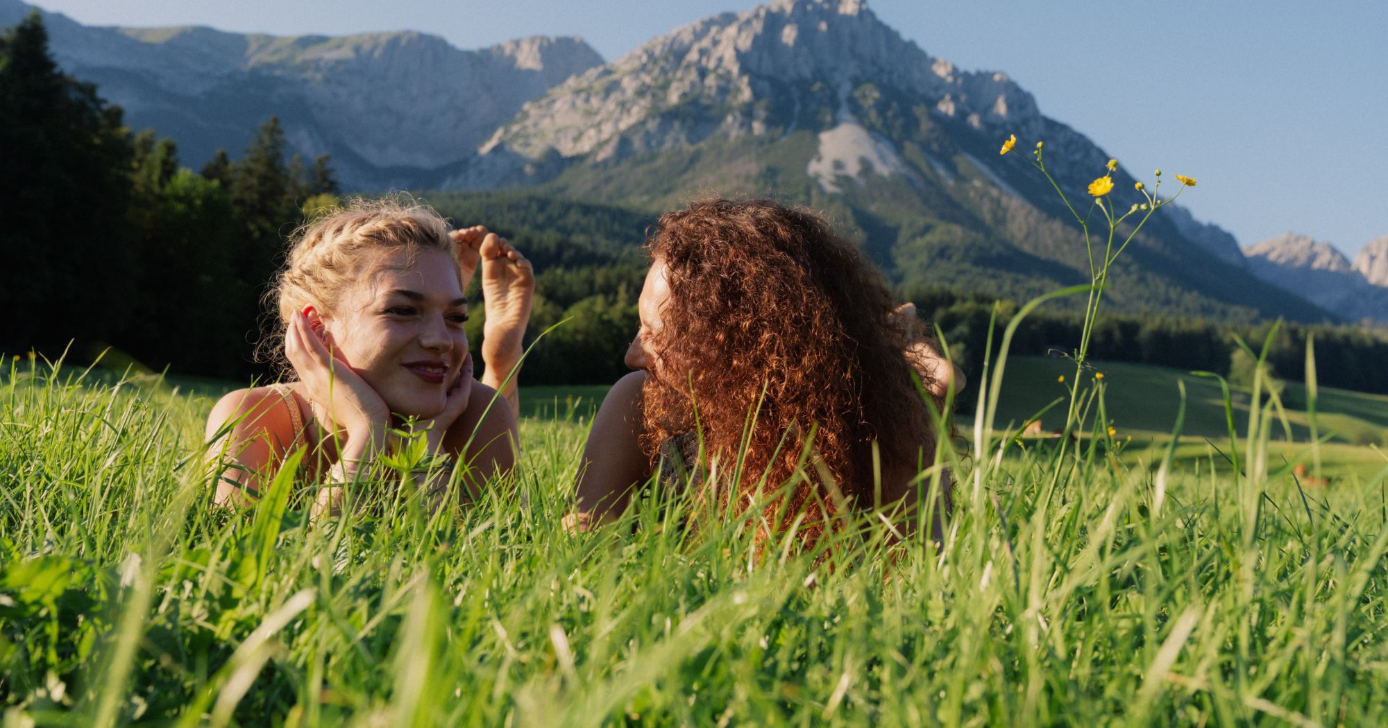 Two women lying in a summer meadow below the Wilder Kaiser