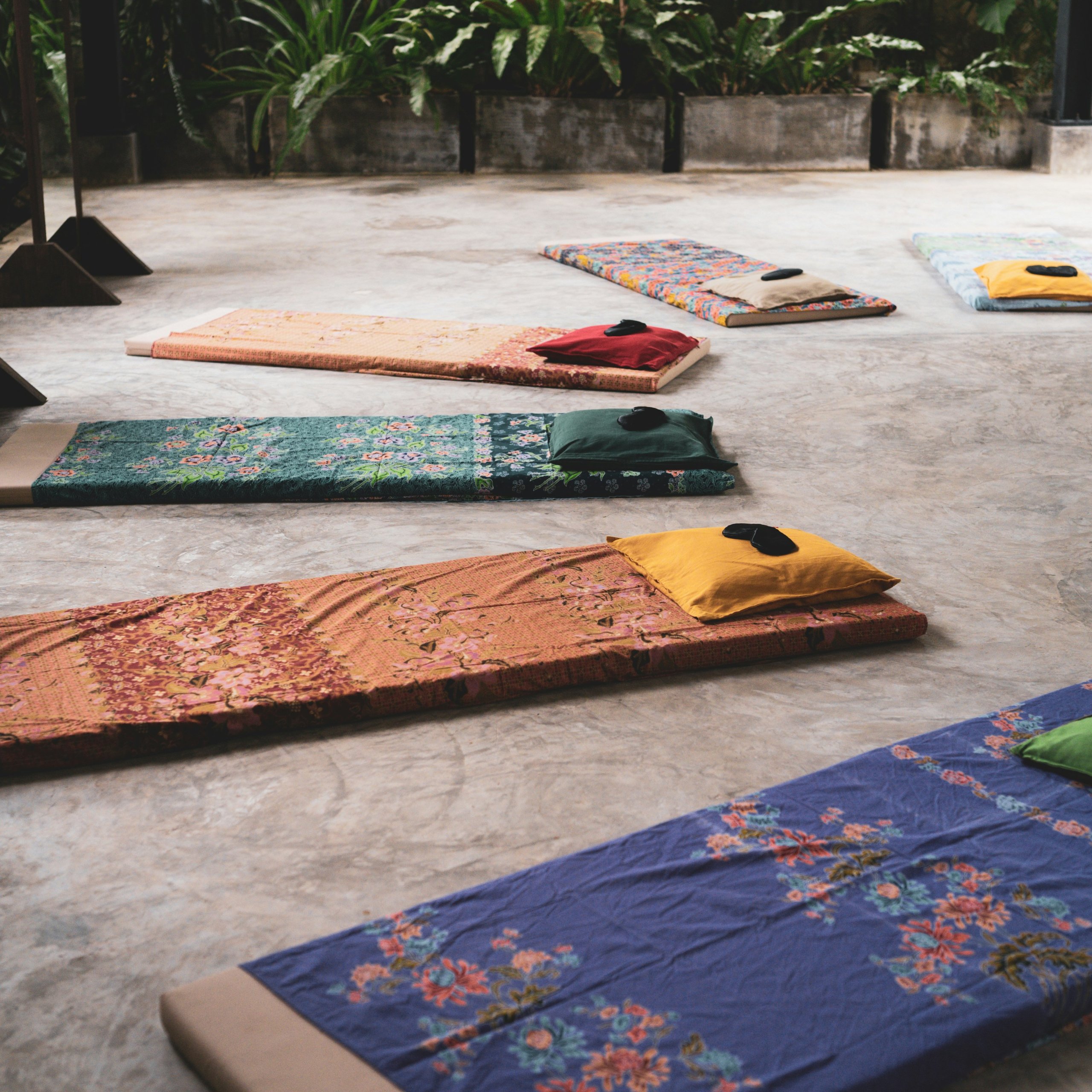 Woven mats and cushions laid out on a stone terrace, ready for a breathwork circle