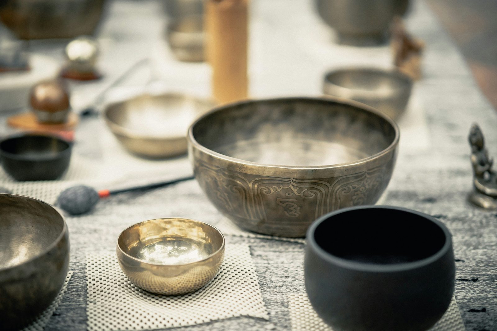 A copper singing bowl and mallet on a woven mat